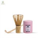 Matcha preparation set with wooden whisk, container, and pink lid on a white background