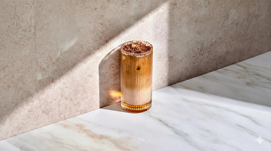 Iced chocolate hazelnut latte made with espresso and milk, topped with cocoa, styled with hazelnuts and chocolate pieces