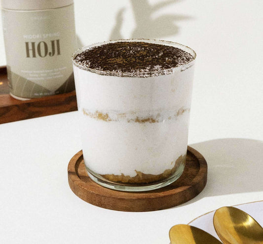 Vegan hoji tiramisu served in a glass, featuring layers of creamy whipped topping and Hojicha powder.