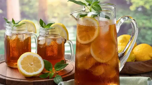 Refreshing iced tea basics with lemon slices and mint leaves in glasses and a pitcher.