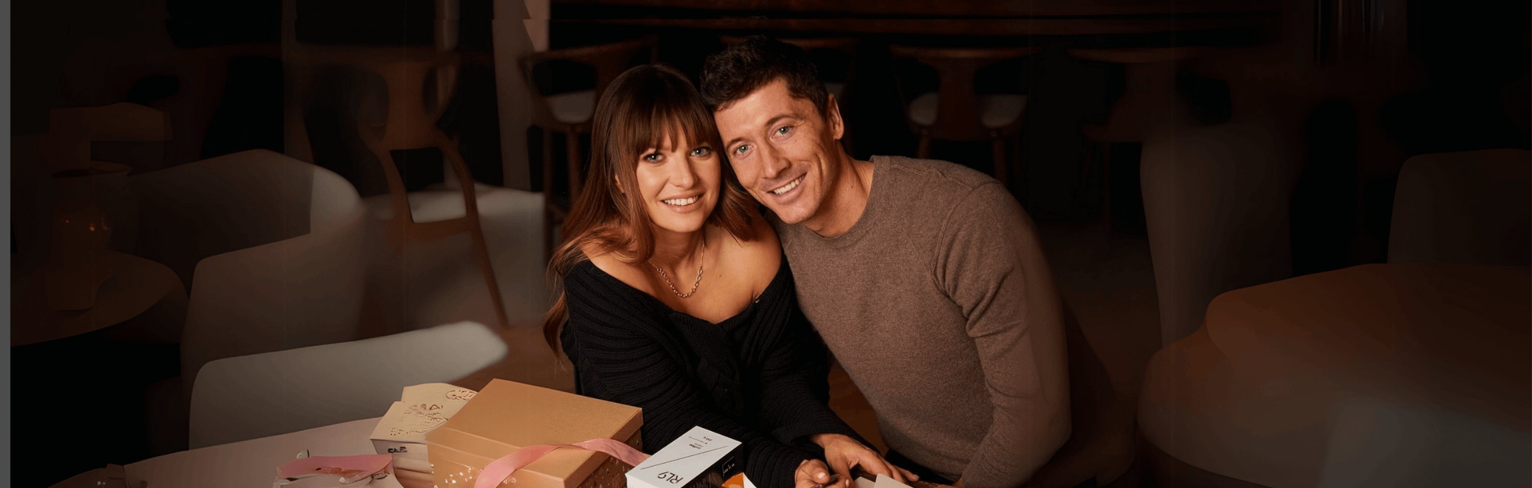 A couple enjoying a cozy moment over a gift hamper filled with coffee, tea, and drinkware in Dubai.