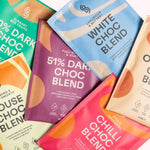 A colorful assortment of Blendsmiths drinking chocolate sachets, featuring flavors like 51% Dark Choc Blend, White Choc Blend, Chilli Choc Blend, and more. Each sachet has a modern design with unique color schemes and highlights key attributes such as veg