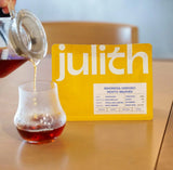 Julith Indonesia Sindoro Mosto Washed specialty coffee pouch with freshly brewed coffee in a glass, featuring jasmine, lychee, green tea and honey tasting notes