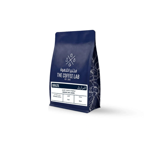 The Coffee Lab Brazil coffee beans in premium dark blue packaging, featuring Brazilian specialty coffee with chocolate, nut, and caramel flavor notes and a natural processing method.