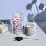 Char-coco Latte package next to a cup of charcoal latte on a stylish table setting.