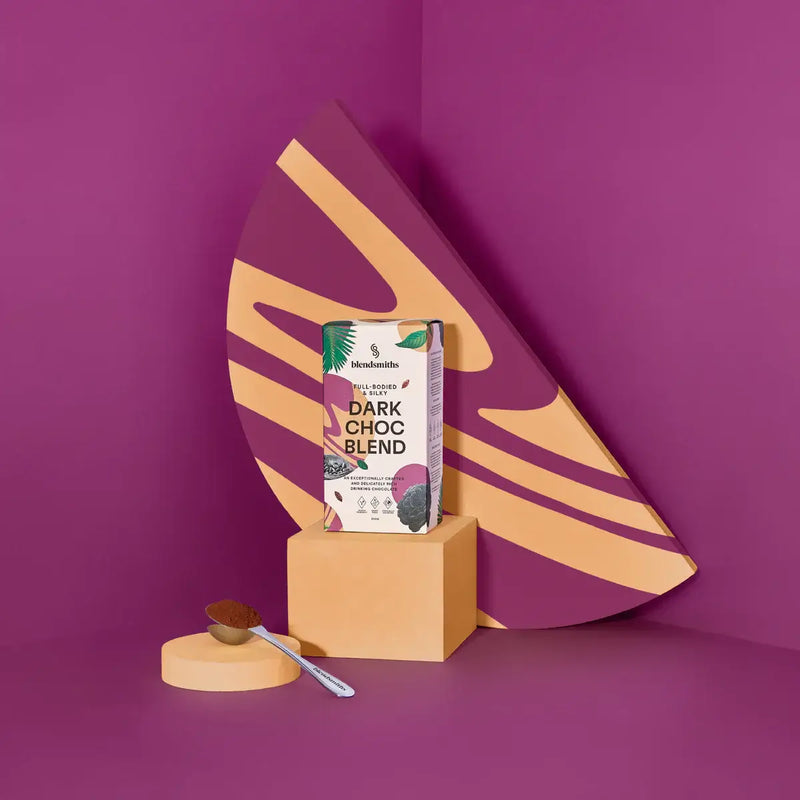 Blendsmiths Dark Choc Blend packaging, featuring a full-bodied and silky drinking chocolate. The 250g box design incorporates deep purple and warm earthy tones, complemented by botanical elements and cocoa imagery. It highlights key product attributes suc