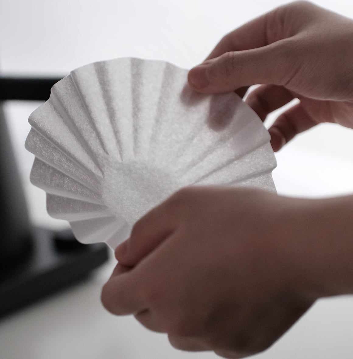 FLO 55 Paper Filters 100x held in hands, showcasing premium design for brewing coffee.