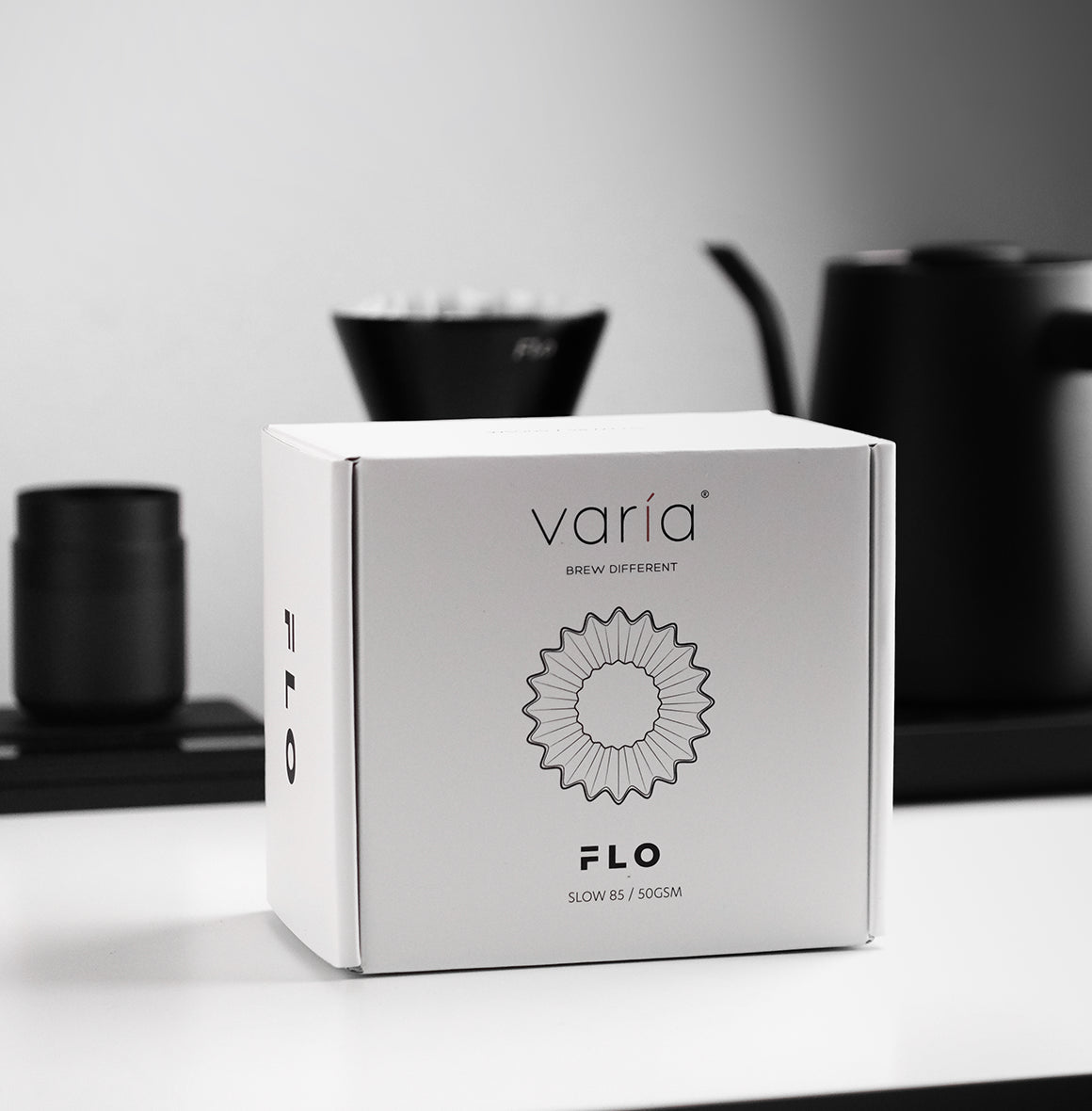 FLO 85 Paper Filters 100x packaging displayed on a modern kitchen countertop with brewing equipment.