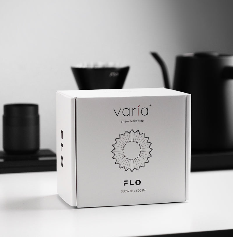 FLO 85 Paper Filters 100x packaging displayed on a modern kitchen countertop with brewing equipment.