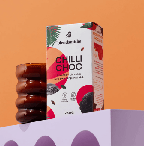 Chilli Chocolate Blend box on a shelf with an orange cup, featuring vegan and gluten-free icons under an orange background.