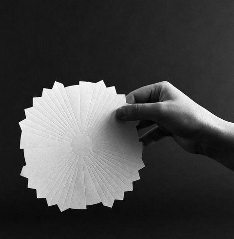 Hand holding Sibarist Fast - Origami Specialty Coffee Paper Filter showcasing its unique design.
