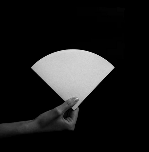 Hand holding Sibarist B3 Cone Coffee Filter against black background, showcasing high-performance design for enhanced pour-over brewing.