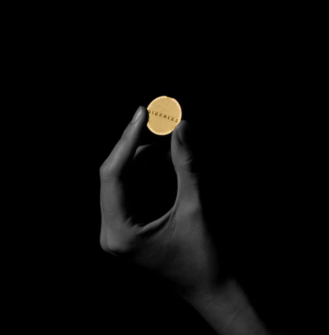 Hand holding Sibarist Booster 22 mesh disc against black background for pour-over coffee brewing enhancement