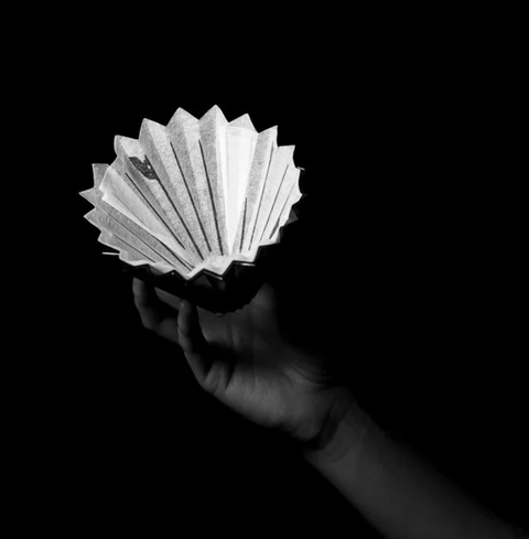 Hand holding Sibarist Fast - Origami Specialty Coffee Paper Filter in dark background