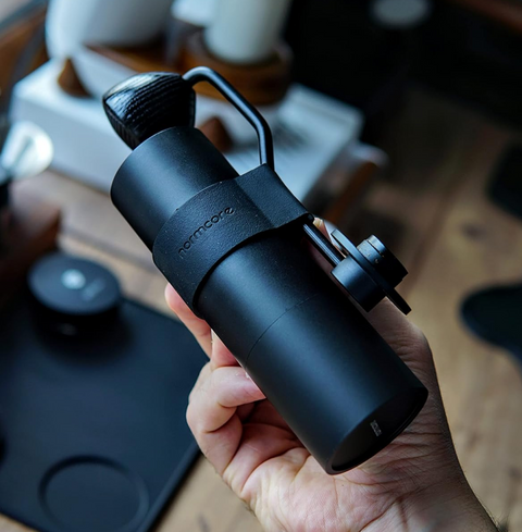 Normcore V2 Manual Coffee Grinder Titanium Plated with ergonomic silicone grip held in hand