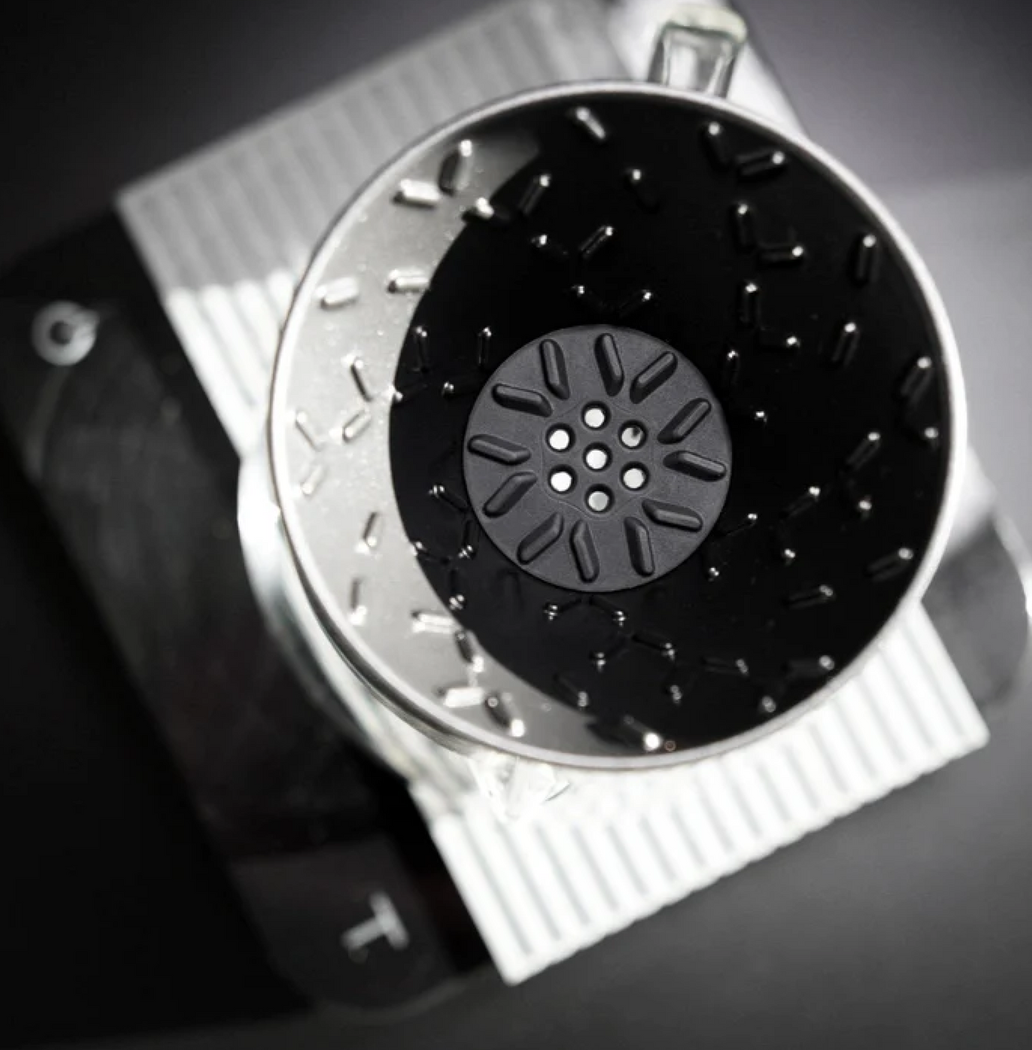 Graycano Coin placed at the base of a coffee dripper, showing optimized water flow and stainless steel construction.