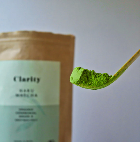 HARU - Organic Ceremonial Matcha in spoon with product package in background, showcasing vibrant green color and fine texture.