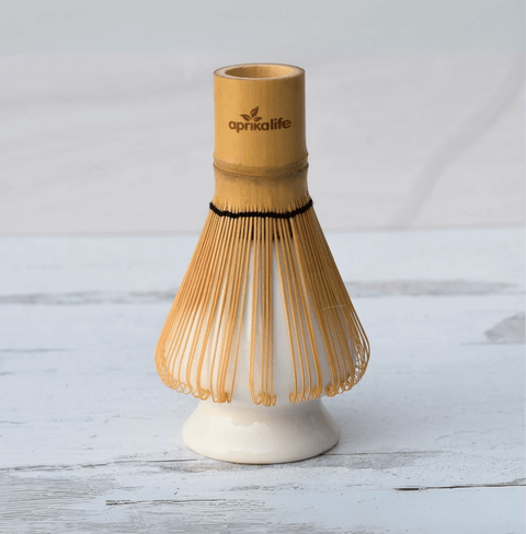 White Whisk Holder cradling a bamboo matcha whisk on a light wooden surface.