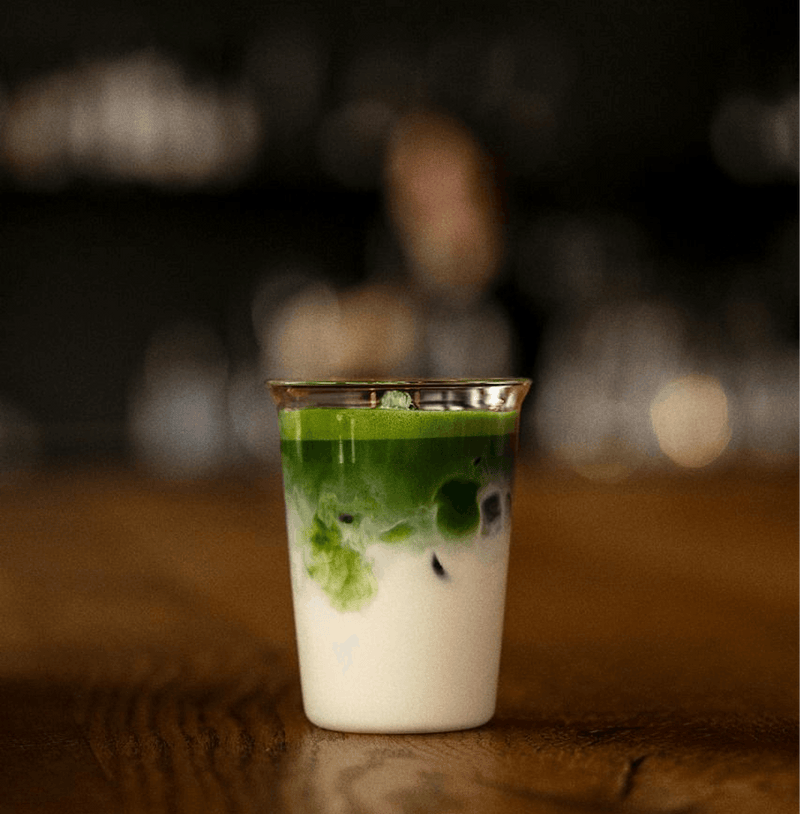 Uji Matcha latte in a clear glass showcasing vibrant green tea layers on creamy milk. Premium matcha sourced from Kyoto.