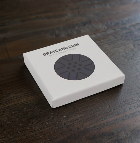Graycano Coin in packaging on wooden surface