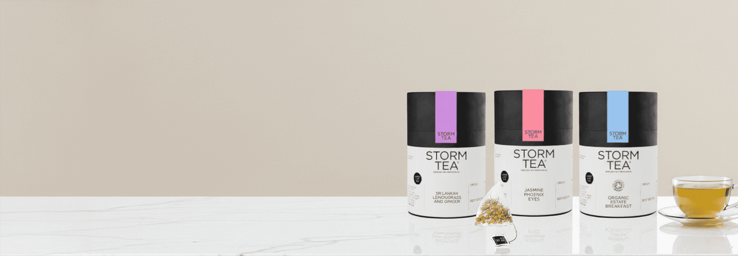 Premium Storm Tea collection featuring three vibrant canisters and a cup of brewed tea on a marble countertop.