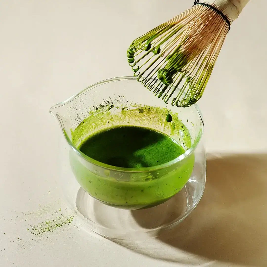 Rare Gold Matcha in glass bowl with whisk, highlighting warm deeper notes from single cultivar, single harvest roasted tencha.