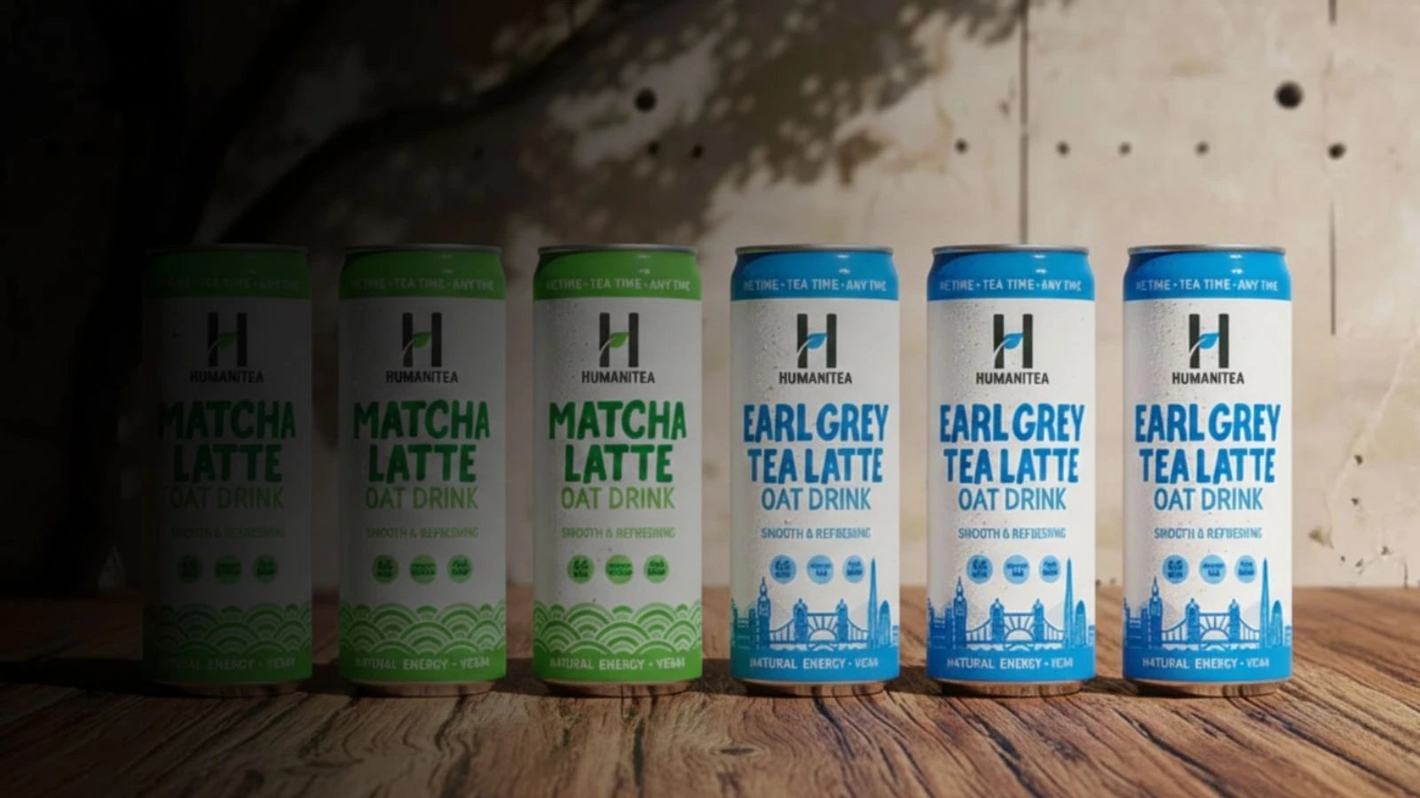 Five cans of Humana tea on a wooden surface with a rustic background.