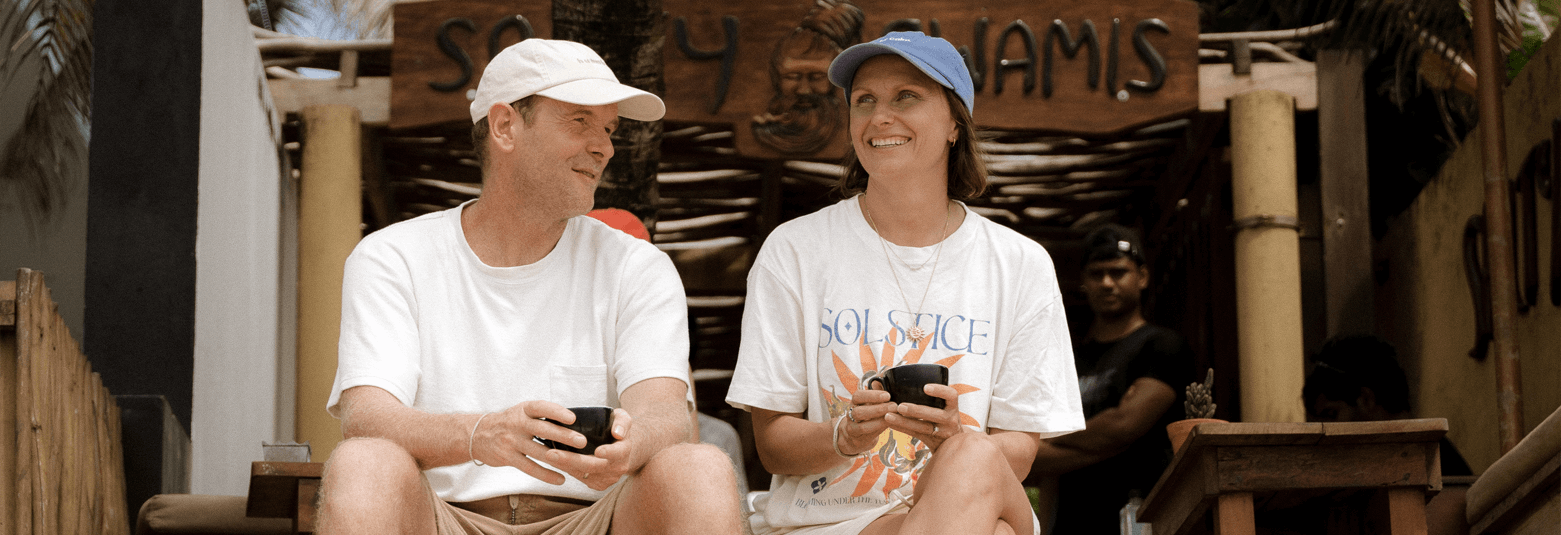 Couple enjoying drinks at a cafe in Dubai, surrounded by palm trees and vibrant decor.
