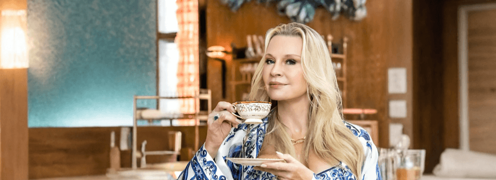 Woman enjoying a cup of coffee or tea in a stylish kitchen, showcasing drinkware and relaxation in Dubai, UAE.