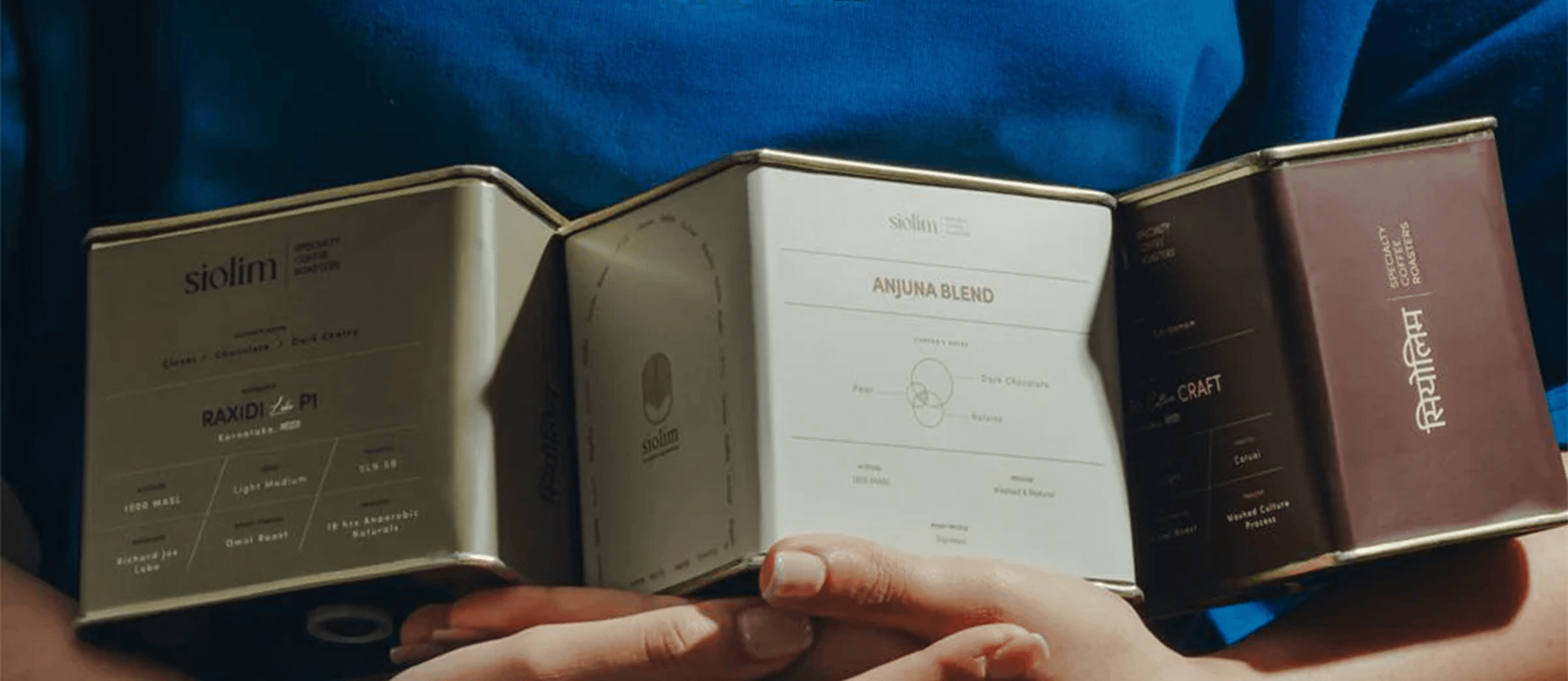 Three small boxes with visible branding held by a person against a blue background