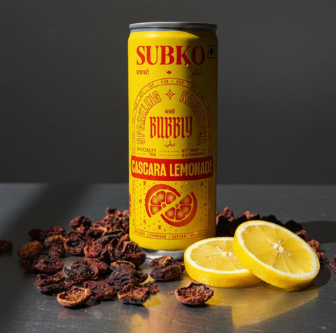 SUBKO Bubbly Cascara Lemonade sparkling kombucha in a yellow can with dried coffee cascara and fresh lemon slices, refreshing fermented specialty beverage.