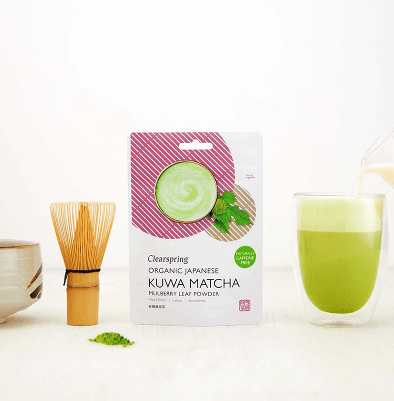Organic Japanese Kuwa Matcha mulberry leaf powder package with matcha whisk and tea cup on a light background.