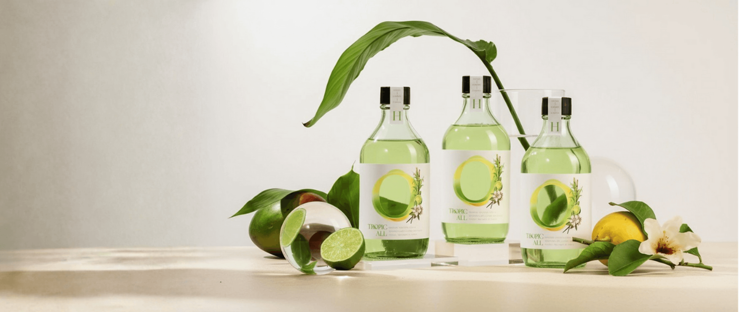 Three green bottles with leafy greens and fruits on a light background