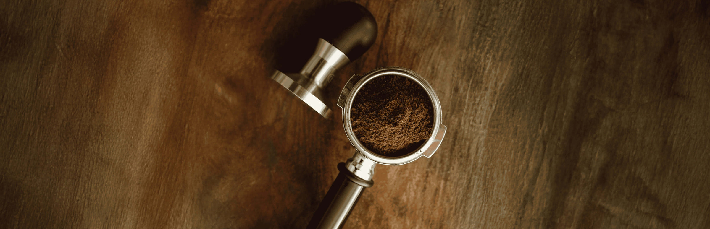 Freshly ground coffee in a portafilter on a wooden table, perfect for coffee lovers in Dubai, UAE.
