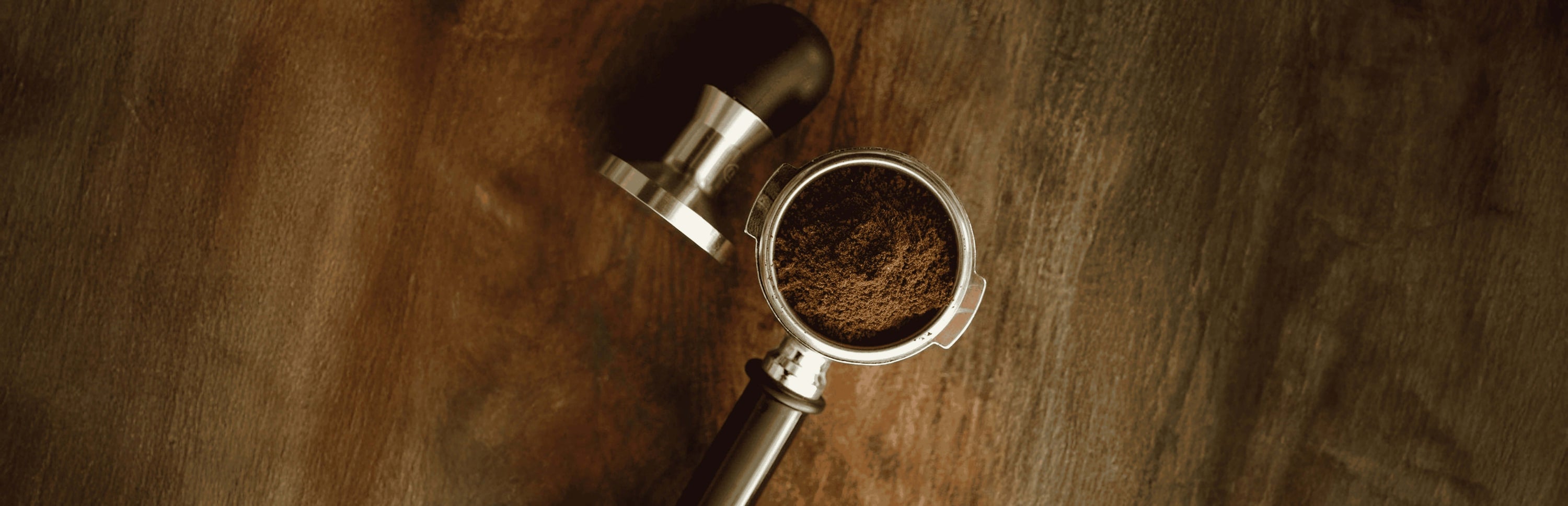Freshly ground coffee in a portafilter on a wooden table, perfect for coffee lovers in Dubai, UAE.