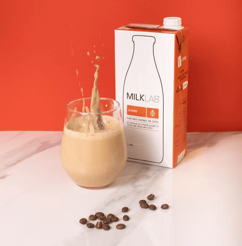 Almond Milk in a glass with coffee beans, showcasing its creamy texture for coffee and matcha drinks.