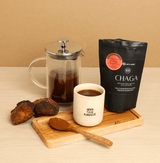 Chocolate Orange Chaga Tea with Chaga mushrooms and brewed tea in a French press and cup on a wooden board.