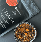 Chocolate Orange Chaga Tea blend with Chaga powder and dried orange pieces in a bowl.