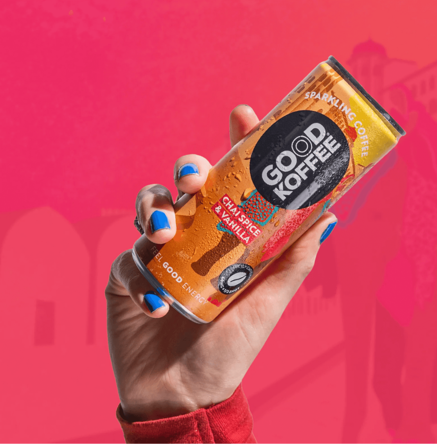 Person holding a can of Chai Spice & Vanilla Sparkling Coffee - India by Good Koffee with a vibrant pink background.