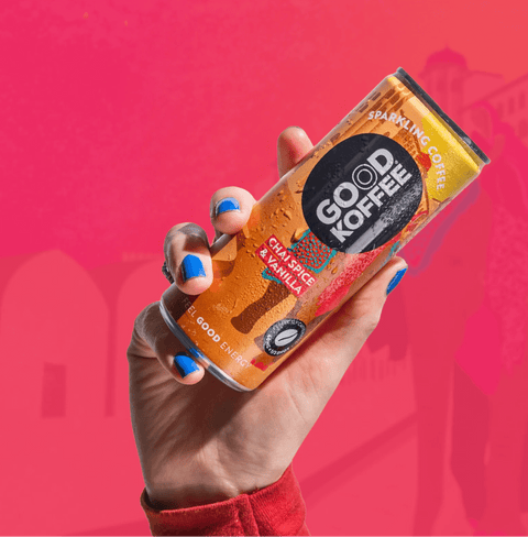 Person holding a can of Chai Spice & Vanilla Sparkling Coffee - India by Good Koffee with a vibrant pink background.