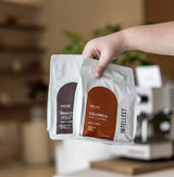 Hand holding Colombia Finca La Esperanza by Intellect Coffee medium roasted specialty coffee bags, single-farm Colombian Caturra washed coffee.