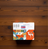 Drip Bag Box - Costa Rica on wooden table, showcasing vibrant packaging with abstract designs and Costa Rican flag.
