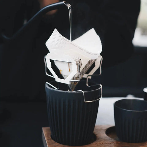 White belt with a black buckle on a stand over a black cup on a wooden surface.