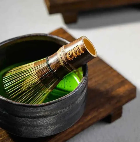 Era Dark Bamboo Chasen — Matcha Whisk immersed in matcha inside a ceramic bowl on a wooden surface.