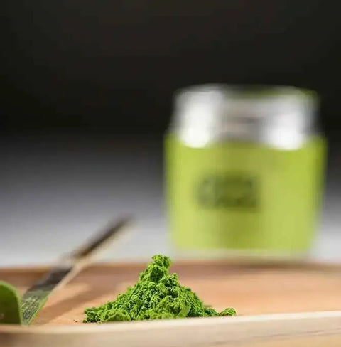 Era Dark Bamboo Chashaku — Matcha Spoon with matcha powder on a wooden tray and green jar in the background.