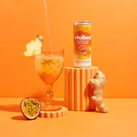 Passion Fruit & Ginger Superfood Infusion with ginger root, fresh passion fruit, and fizzy drink in a glass on an orange background.