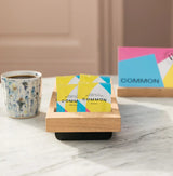 Instant Box containing sachets of instant coffee on a marble table with a cup of coffee.