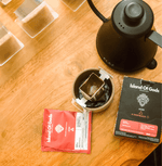 Variety of Island of Gods drip bag coffee boxes displayed on a rustic surface, showcasing vibrant packaging and flavors.