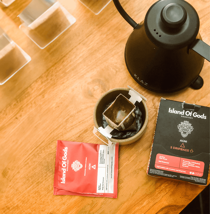 Variety of Island of Gods drip bag coffee boxes displayed on a rustic surface, showcasing vibrant packaging and flavors.