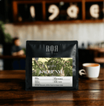 Kenya Kachunyu coffee bag on a cafe table, showcasing its vibrant and complex East African flavors.